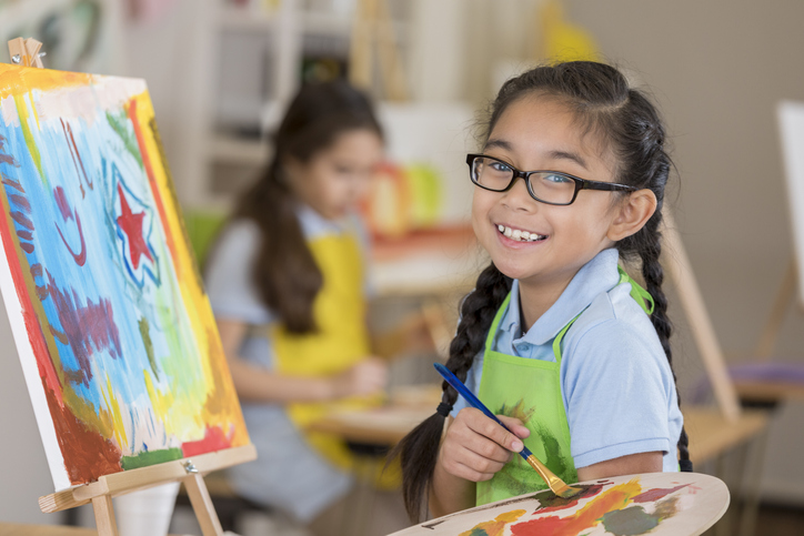 uśmiechnięta dziewczynka malująca obraz